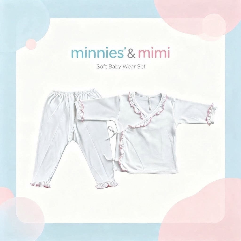 A baby girl's two-piece soft wear set by minnies & mimi, featuring a white long-sleeve top with pink ruffle trim and matching white pants with ruffle hems, displayed on a light cream background with pastel blue and pink graphic accents.